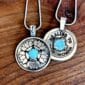 Two silver Healing Pendants with turquoise stones on them.