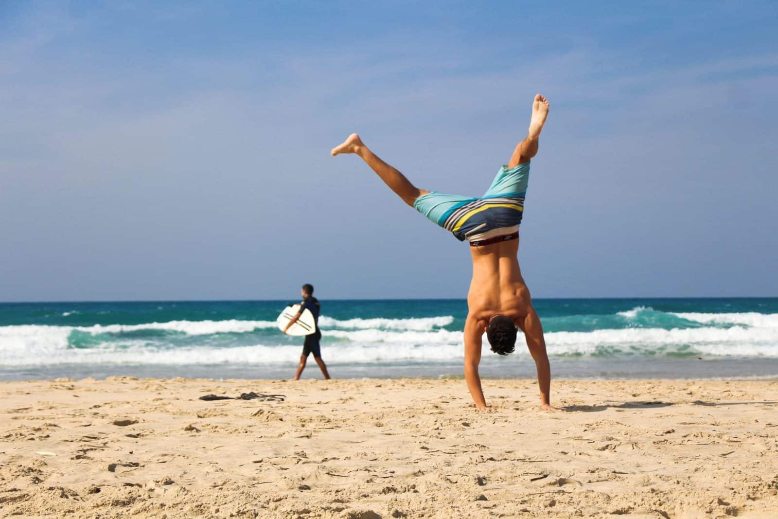 A man doing a handstand on the beach.