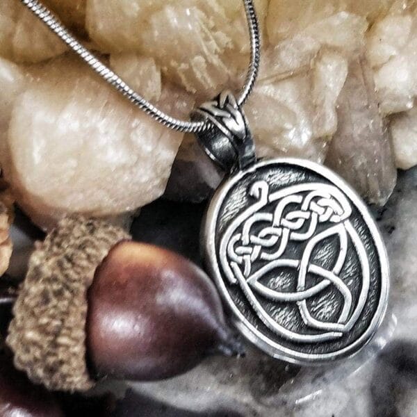 A silver pendant with a celtic design on it.