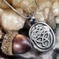 A silver pendant with a celtic design on it.
