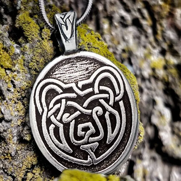 A silver pendant with a bear on it.