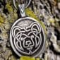 A silver pendant with a bear on it.