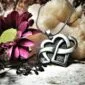 A silver heart shaped pendant with a flower on it.