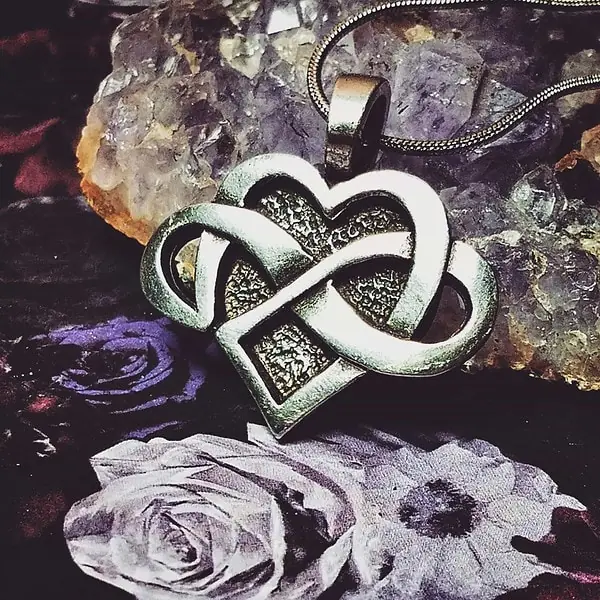 A heart shaped pendant with an infinity symbol on it.