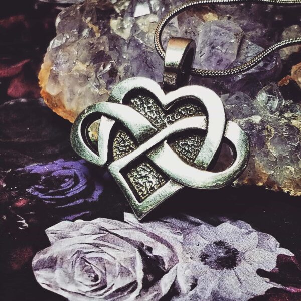 A heart shaped pendant with an infinity symbol on it.
