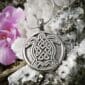A celtic turtle pendant is sitting on a rock.