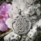 A celtic turtle pendant is sitting on a rock.