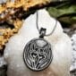 A silver pendant with a wolf's head on it.