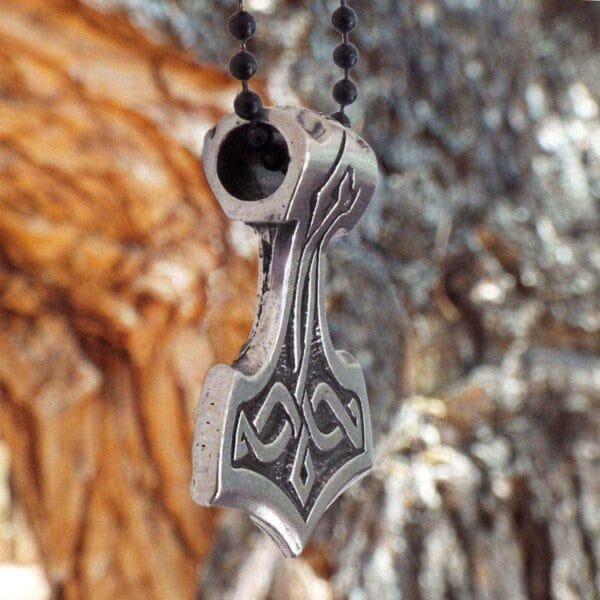 A pendant with a hammer on it hanging from a tree.