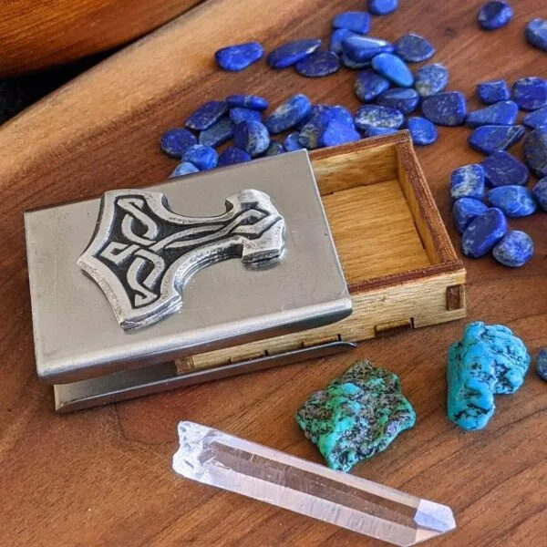 A wooden box with stones and a thor hammer.