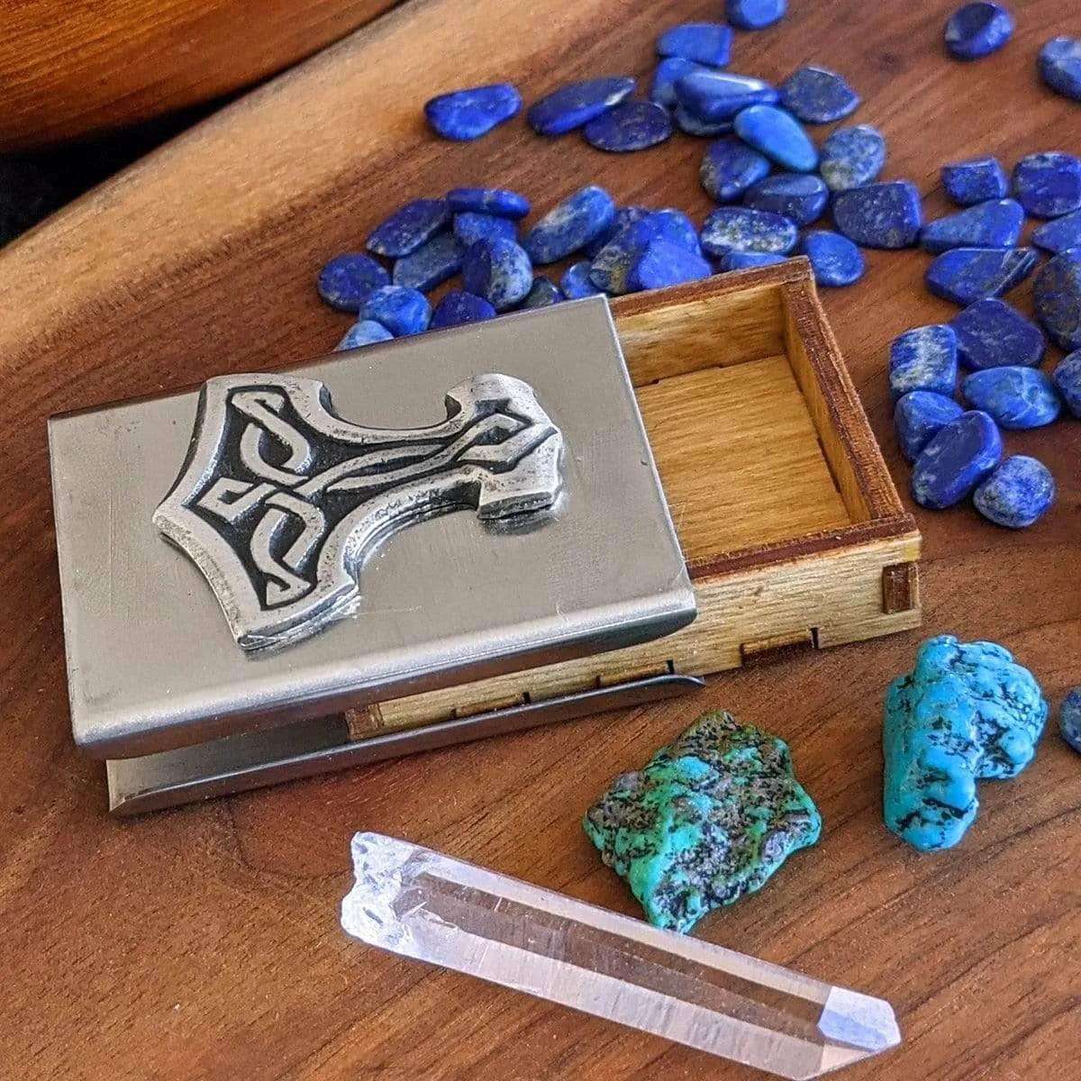 A wooden box with stones and a thor hammer.