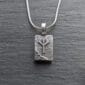 A silver pendant with a viking symbol on it.