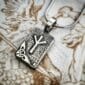A silver pendant with a viking symbol on it.
