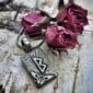 A pendant with a viking symbol and roses on it.