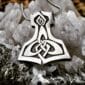 A silver thor hammer pendant on top of crystals.