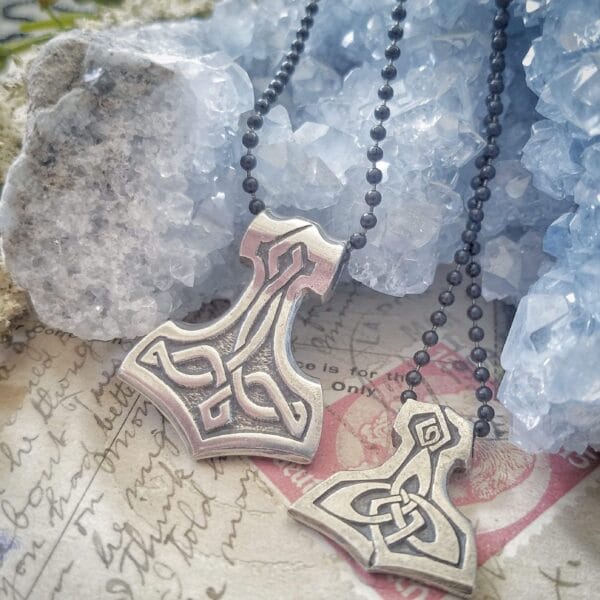 Two thor hammer necklaces on top of a piece of paper.
