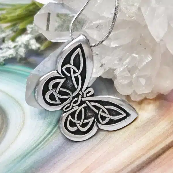 A silver butterfly pendant on top of a crystal.