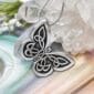 A silver butterfly pendant on top of a crystal.