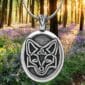 A pendant with a fox on it in the woods.