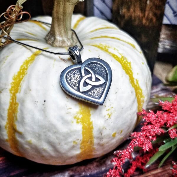 A pendant with a celtic heart on top of a pumpkin.