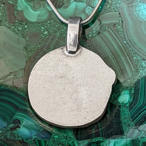 A silver pendant with a circle on it.