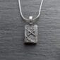 A silver pendant with a viking symbol on it.