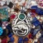A silver pendant with a mermaid and emeralds.