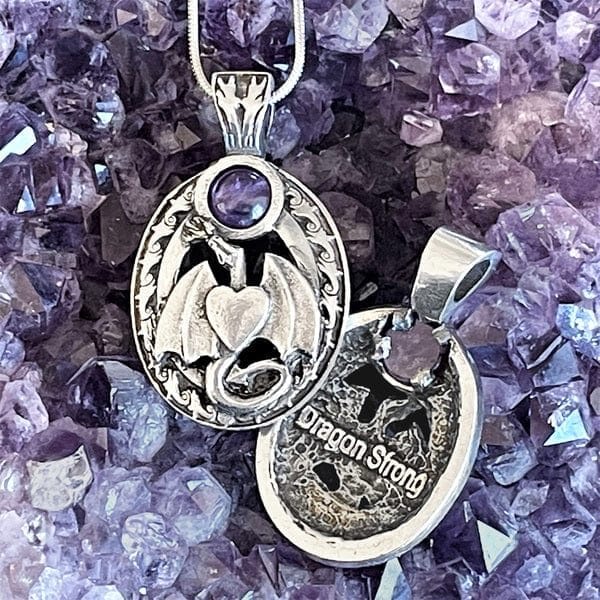 A silver pendant with a dragon on it.