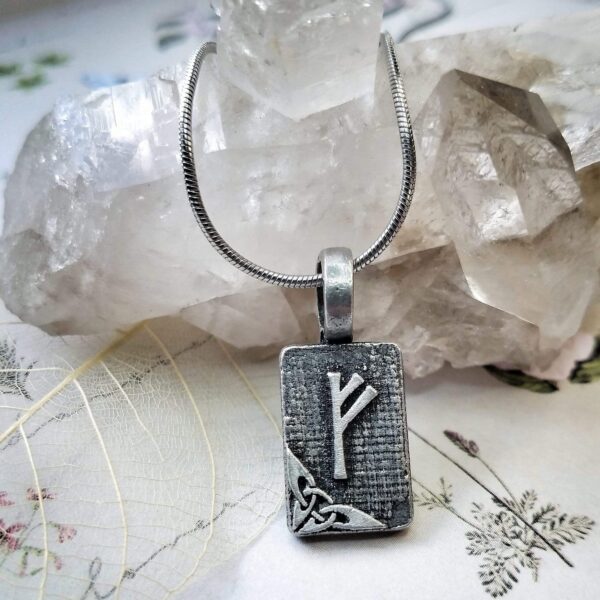 A silver necklace with a viking symbol on it.