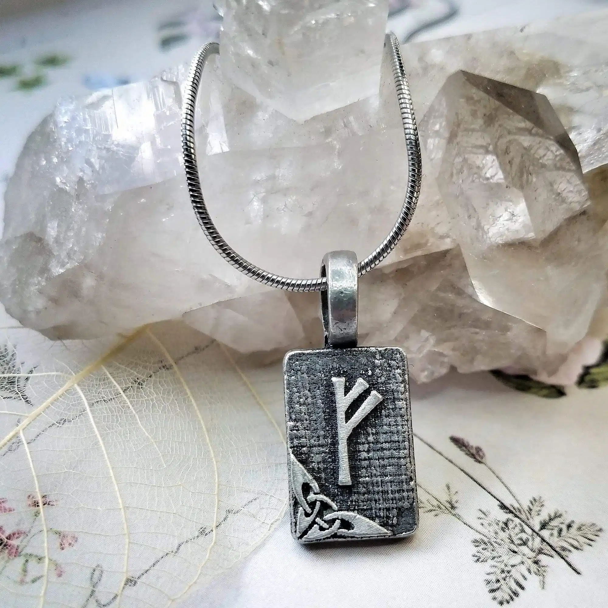 A silver necklace with a viking symbol on it.
