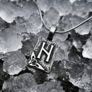 A silver pendant with the letter h on it.