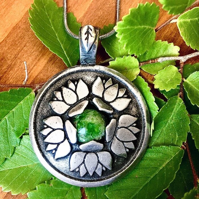 A silver tone pendant with a lotus flower on it.