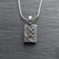 A silver necklace with a celtic symbol on it.