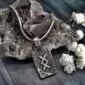 A silver necklace with a viking symbol on it.