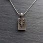 A silver pendant with a leaf on it.