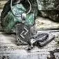 A silver pendant with a leaf on it.