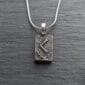 A silver necklace with a viking symbol on it.