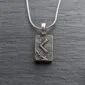 A silver necklace with a viking symbol on it.