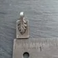A small silver leaf charm on a ruler.
