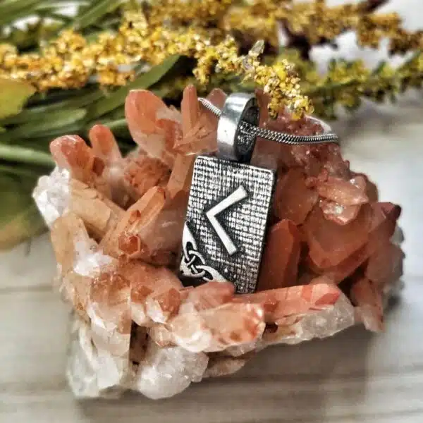 A silver pendant with a viking symbol on it.