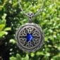 A celtic locket with a blue stone on it.