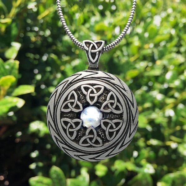 A silver celtic pendant with a moonstone on it.