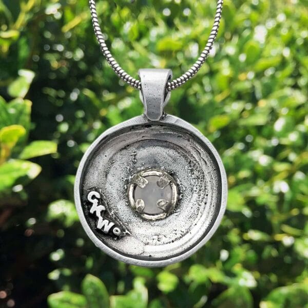 A silver pendant with the word love on it.