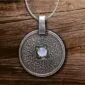 A silver pendant with a blue stone on it.
