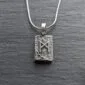 A silver pendant with a celtic design on it.