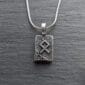 A silver necklace with a viking symbol on it.