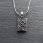 A silver necklace with a viking symbol on it.