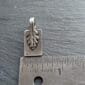 A small silver leaf charm on a ruler.