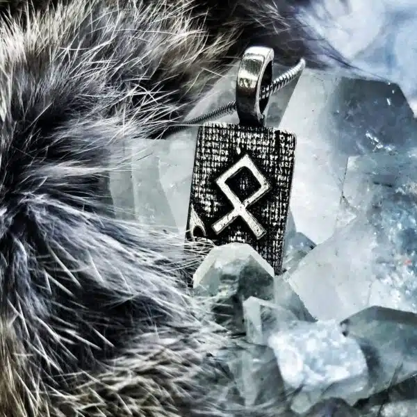 A silver pendant with a viking symbol on it.