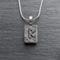 A silver necklace with a viking symbol on it.